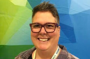 Christa Duvall for pflag canada in front of green and blue geometric wall